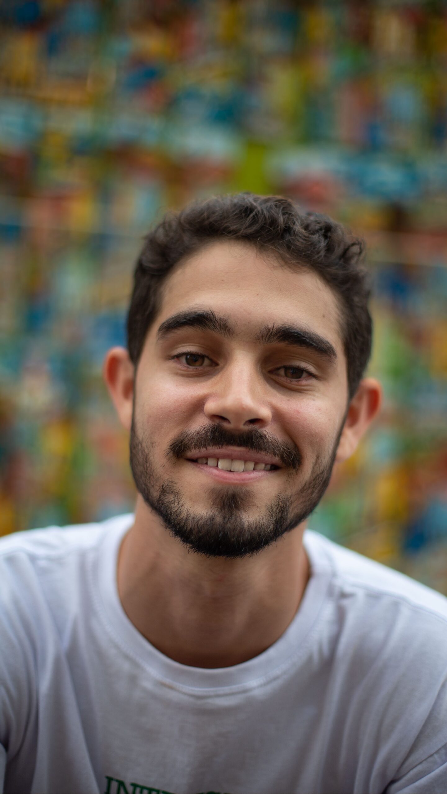 Portrait of a young man smiling with a vibrant, colorful abstract background.