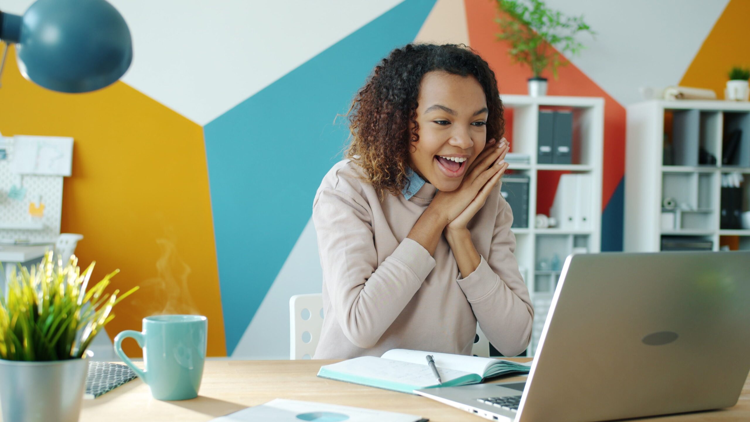 Joyful woman experiencing success while working on a laptop from home.