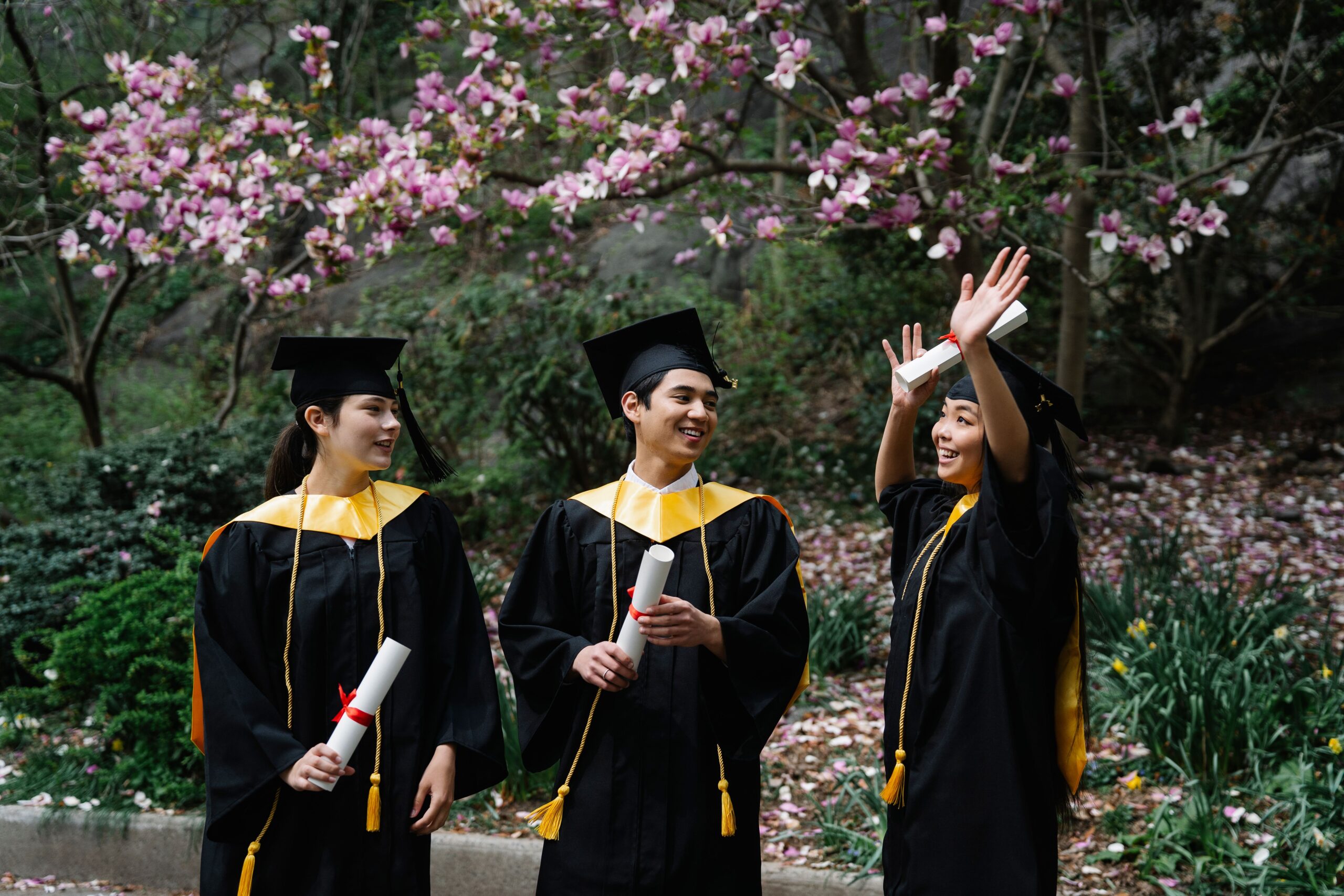 Happy graduates celebrating their achievement outdoors in springtime.